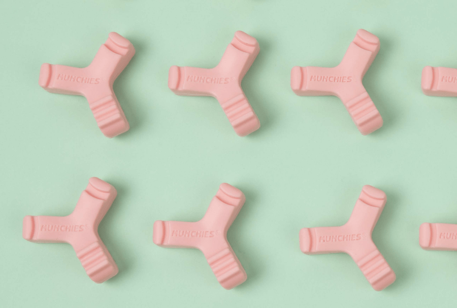 Top down view of six Pink Munchies® EPS lined up against green background